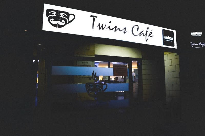 Twins Café sign and entrance lit up in the evening